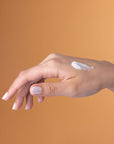Hand applying cream on a brown background