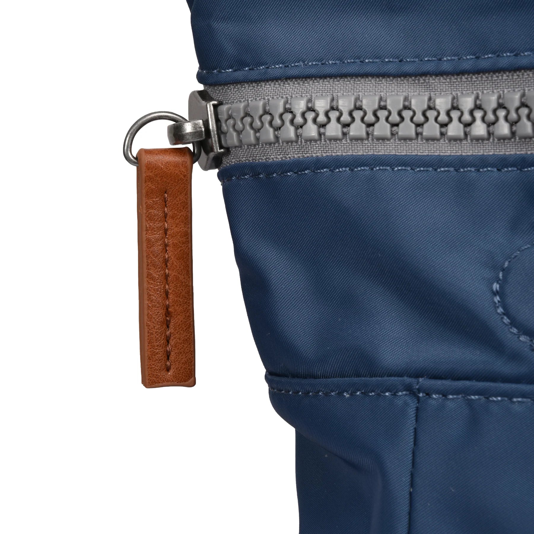 Close-up of a blue jacket zipper with a brown leather pull tab on a white background