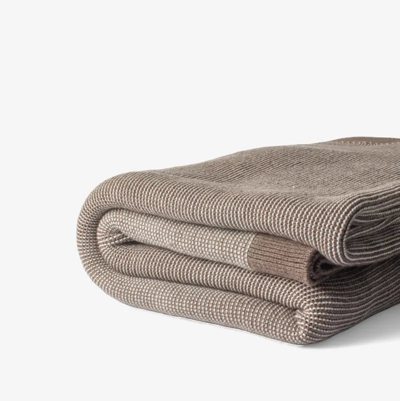 Folded beige blanket on a light gray background