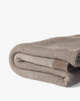 Folded beige blanket on a light gray background
