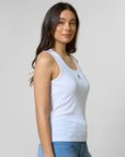 Woman wearing a light blue tank top and jeans against a plain background
