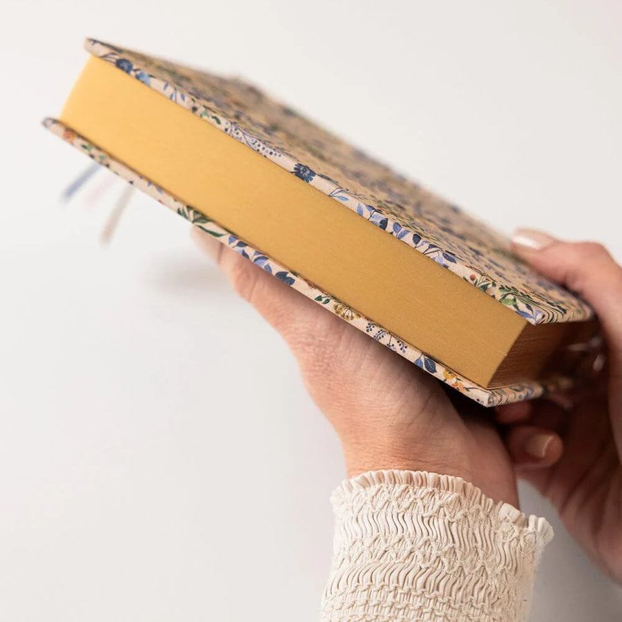 Hand holding a yellow notebook with a patterned cover on a white background