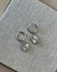 Silver rings with floral designs on a textured gray surface
