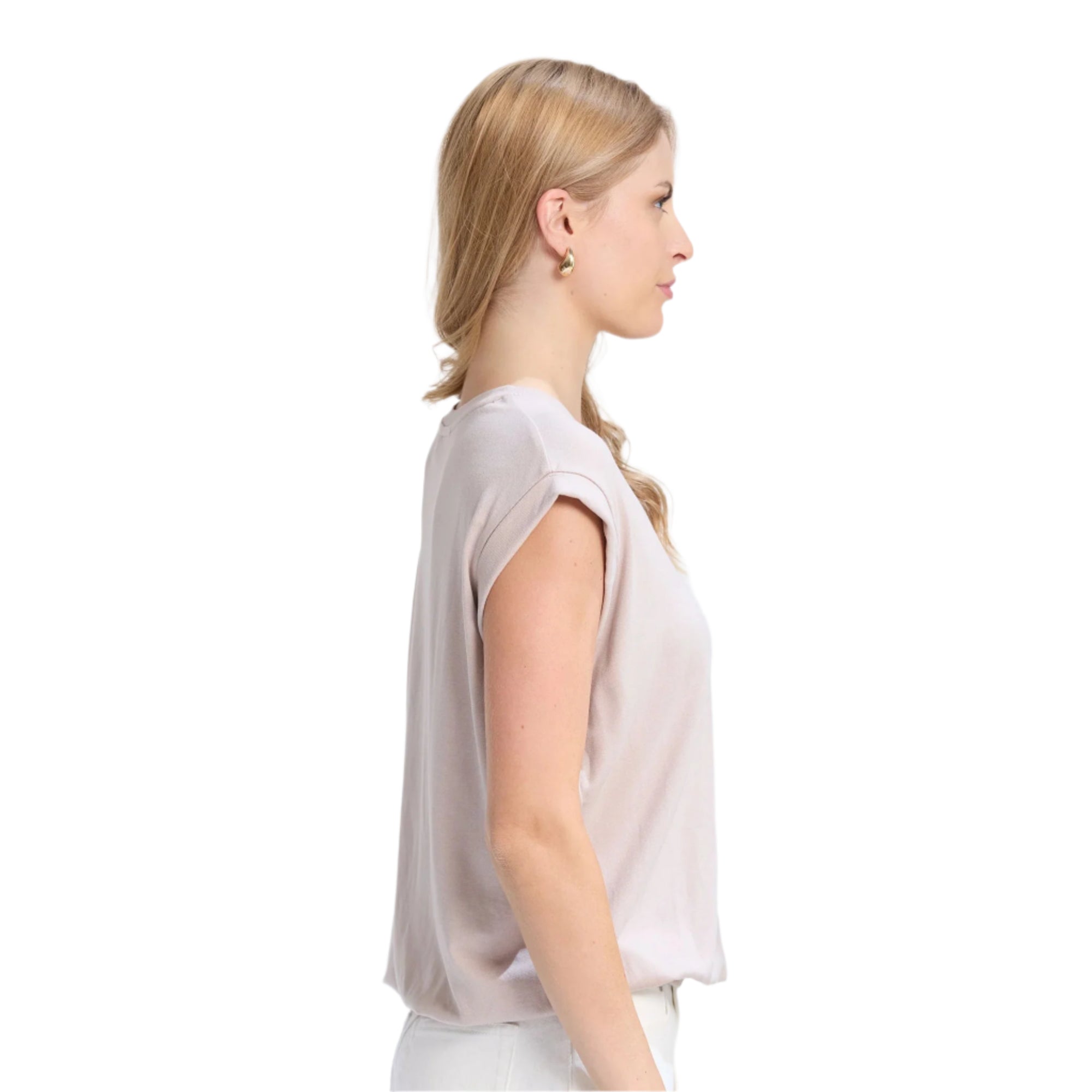 Woman wearing a light pink blouse and white pants on a white background