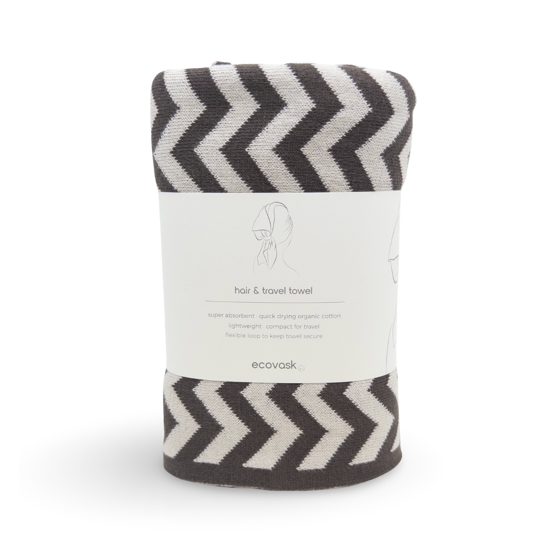 A rolled-up gray and off-white chevron-patterned cotton towel with a white paper label band in the center. The label reads 'ecovask' and 'hair &amp; travel towel'.