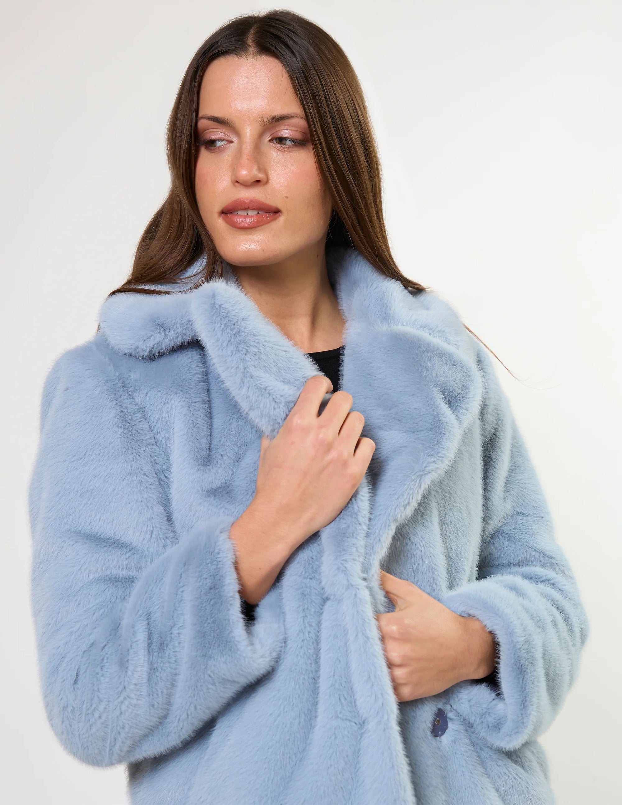Woman wearing a light blue fur coat against a white background