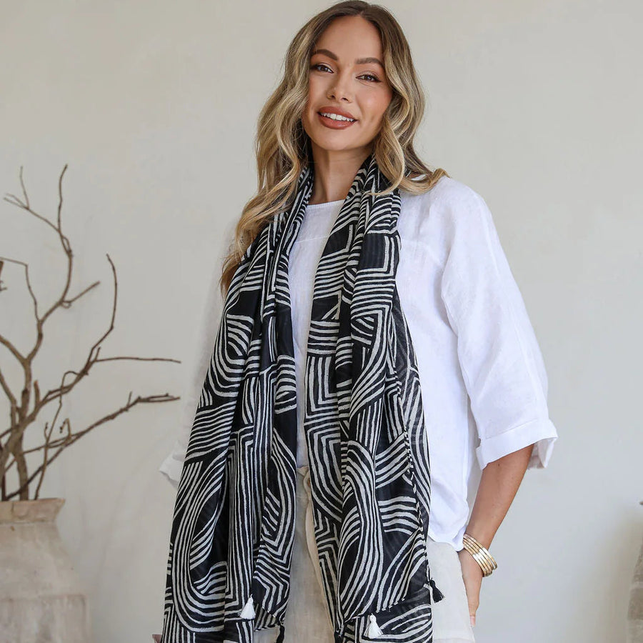 Woman wearing a black and white patterned scarf in a minimalistic room.