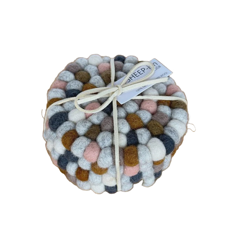 Round woven coaster with multicolored pattern on a wooden surface