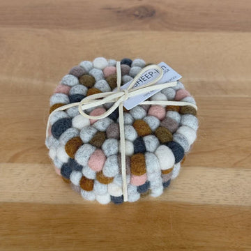 Round woven coaster with multicolored pattern on a wooden surface