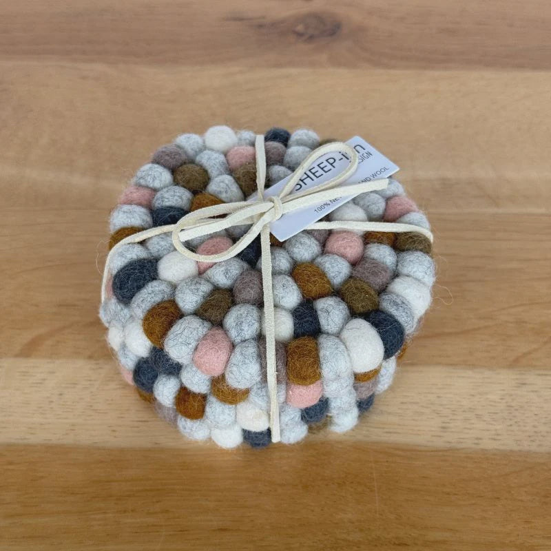 Round woven coaster with multicolored pattern on a wooden surface