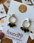 Gold hoop earrings with black beads on a 'foundry & co' card.