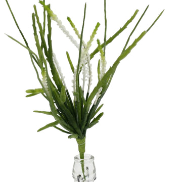 Artificial green plant in a clear glass vase on a white background