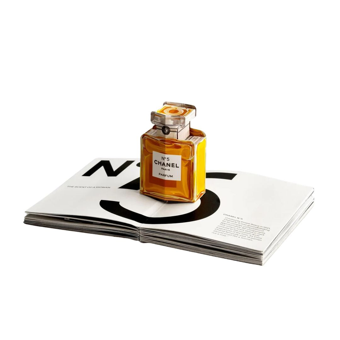 Chanel perfume bottle on an open magazine with a white background