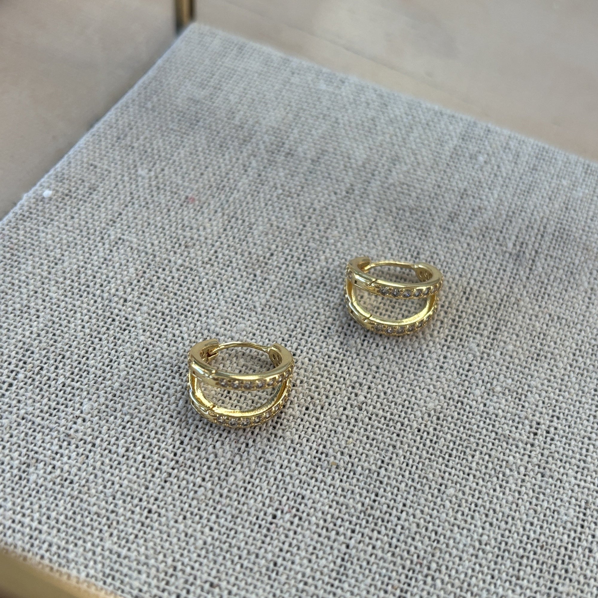 Gold hoop earrings on a textured gray surface