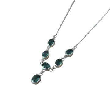 Necklace with green gemstones on a light wooden surface