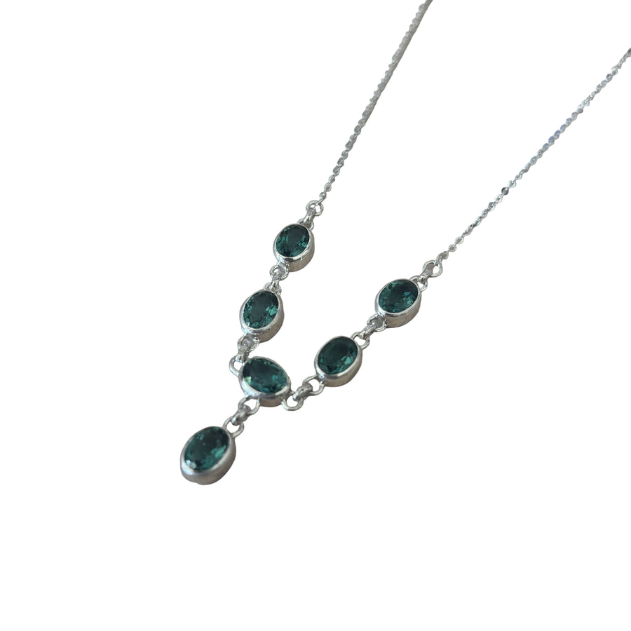 Necklace with green gemstones on a light wooden surface