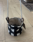 Black and white patterned fabric basket with handles on a wooden floor.