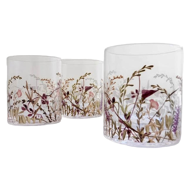 Three glass tumblers with floral and bird design on a white surface