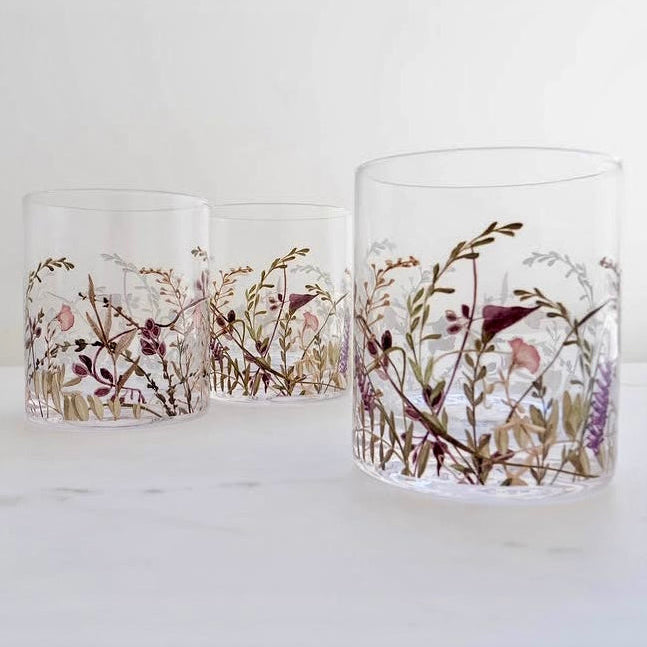 Three glass tumblers with floral and bird design on a white surface