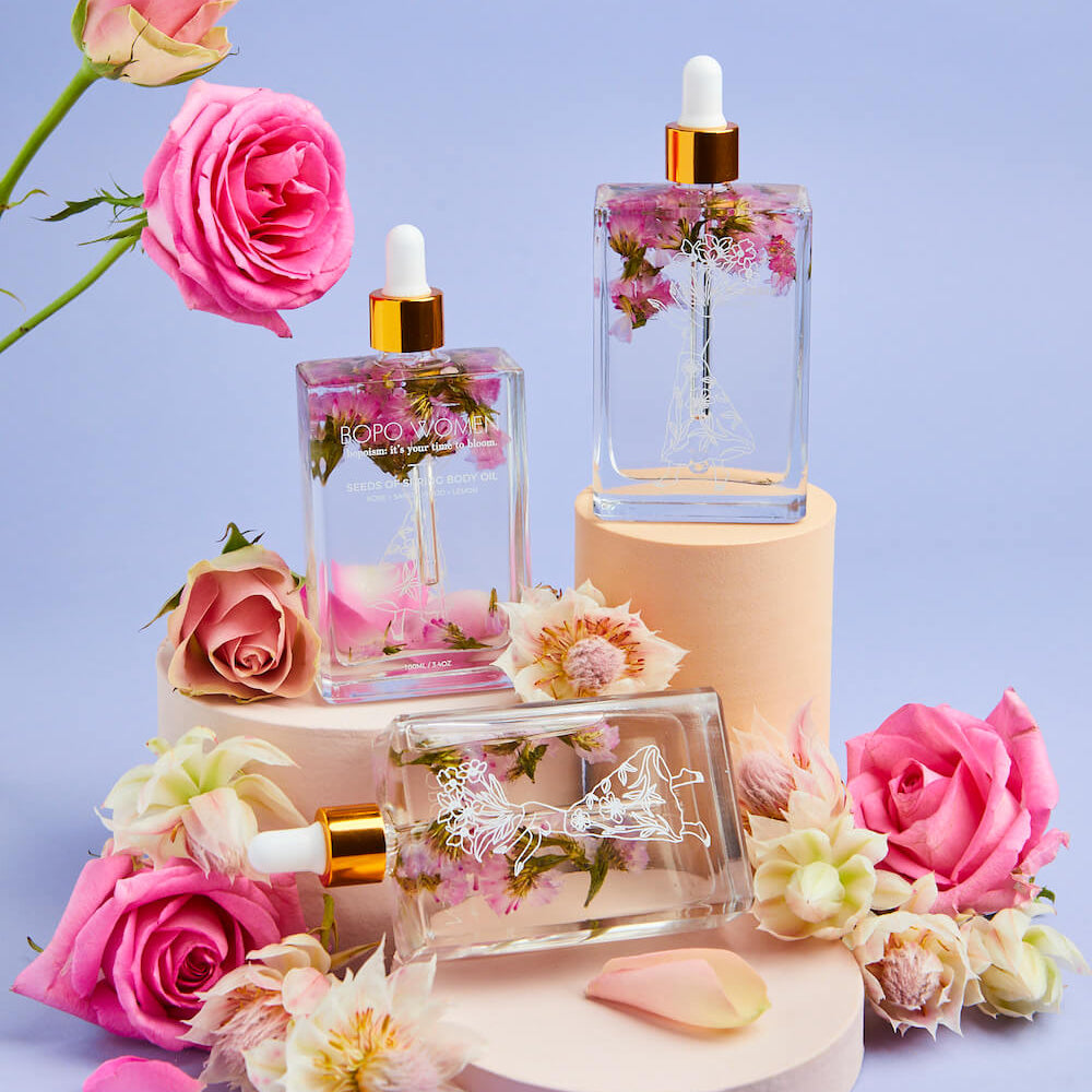 Cosmetic products with flowers on a light purple background
