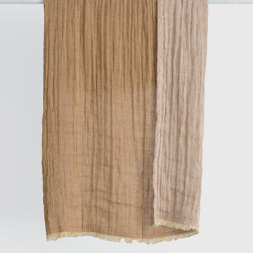 Beige scarf with frayed edges on a white background