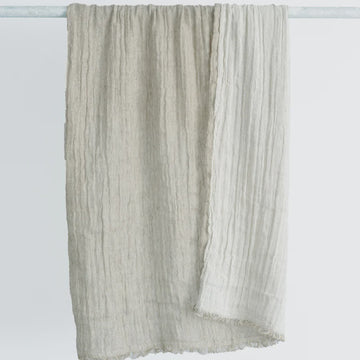 Textured scarf draped over a white rod on a light gray background