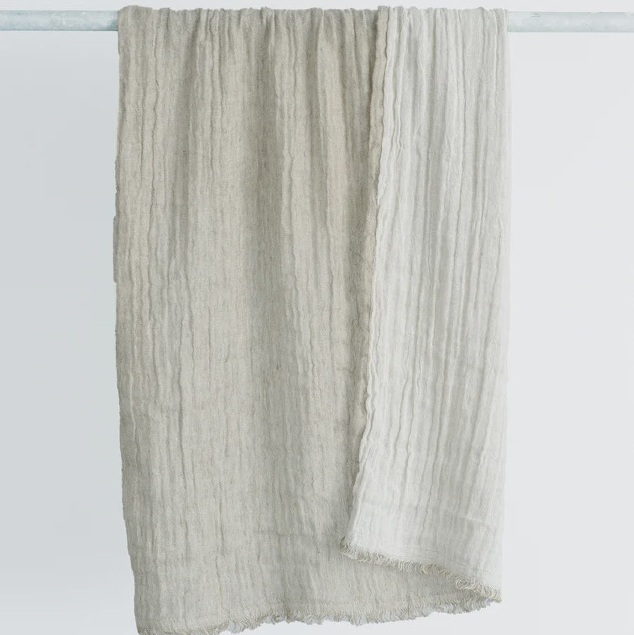 Textured scarf draped over a white rod on a light gray background