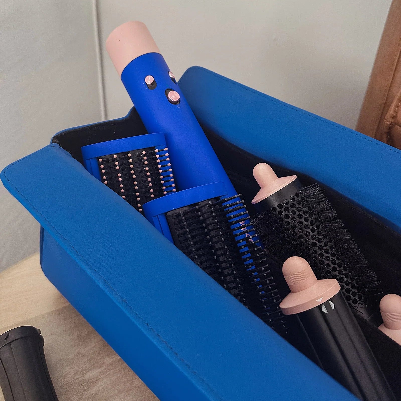 Set of hair styling tools including a blue curling iron and black brushes in an open blue box.