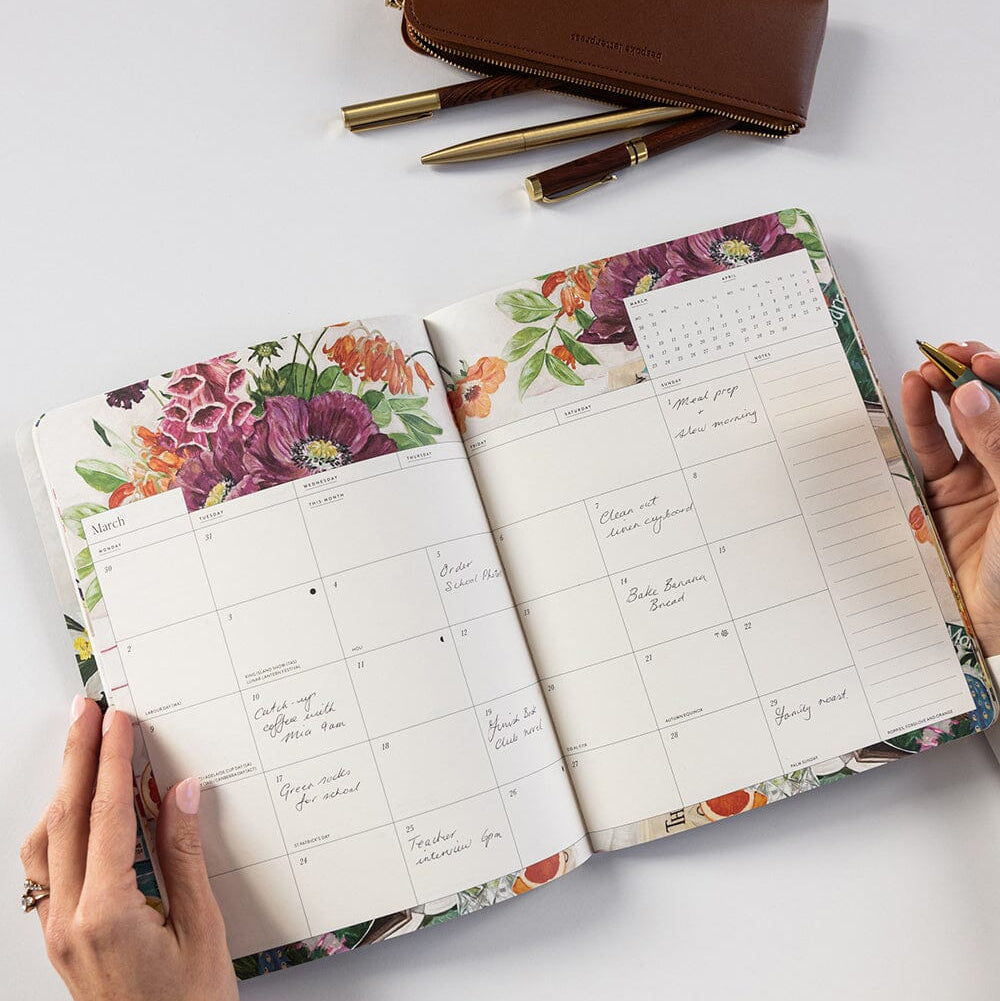 Floral planner with a pen and pencil case on a light surface