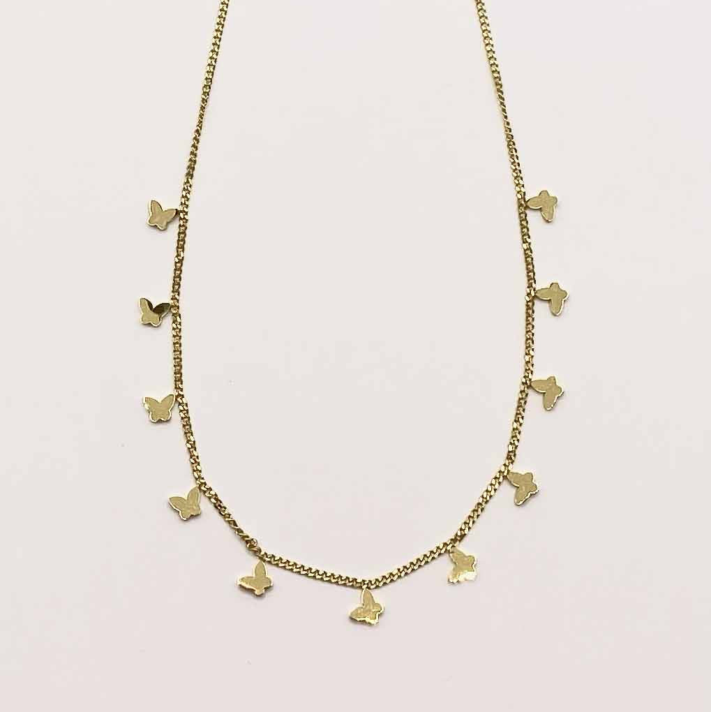 Gold necklace with small pendants on a light pink background