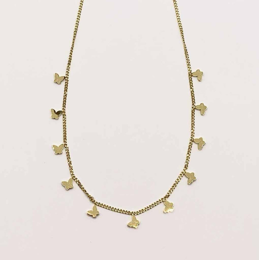 Gold necklace with small pendants on a light pink background