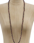 A long beaded necklace with dark reddish-brown faceted beads displayed on a beige fabric mannequin torso against a white background.