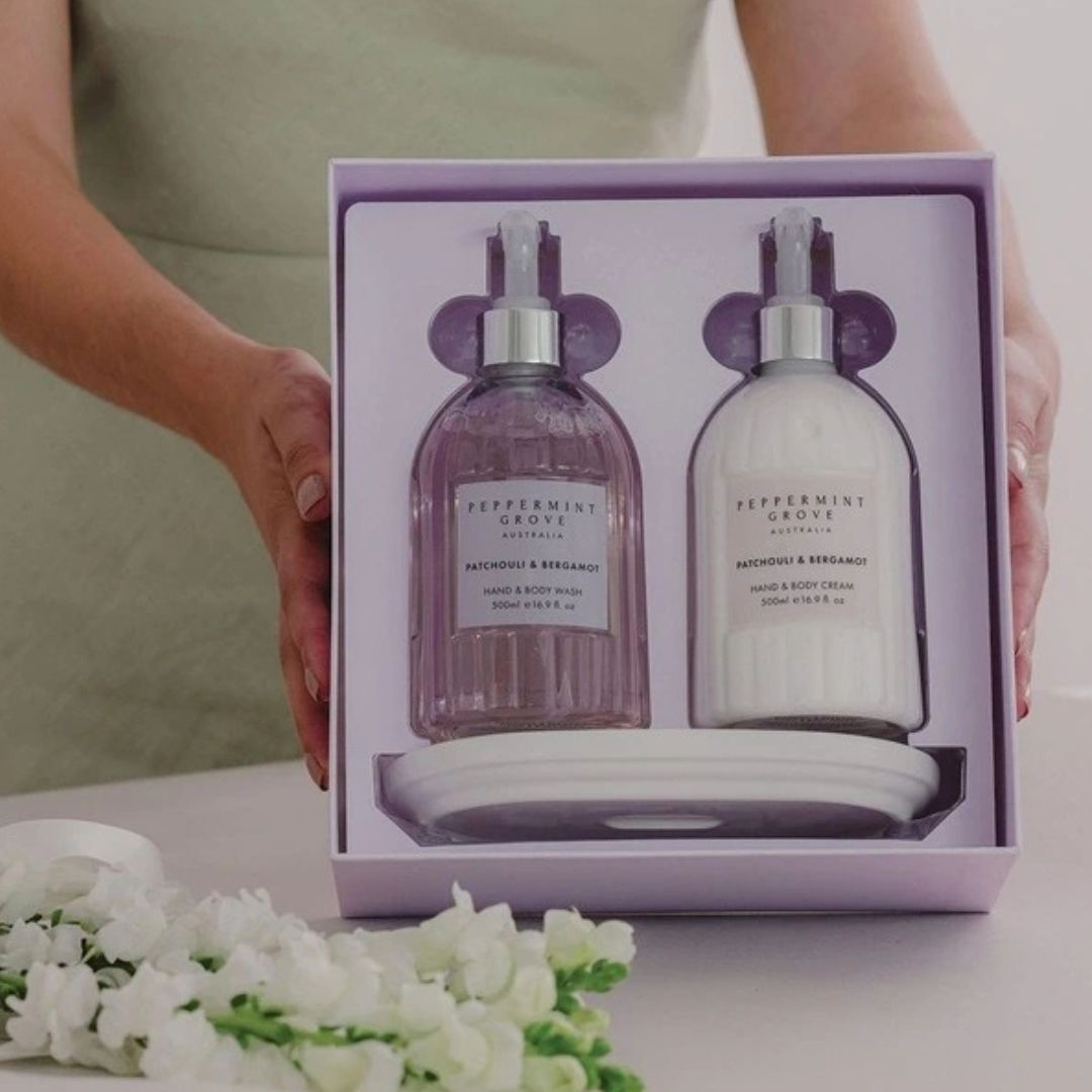 Two bottles of peppermint and eucalyptus body wash in a gift box with a person holding it.
