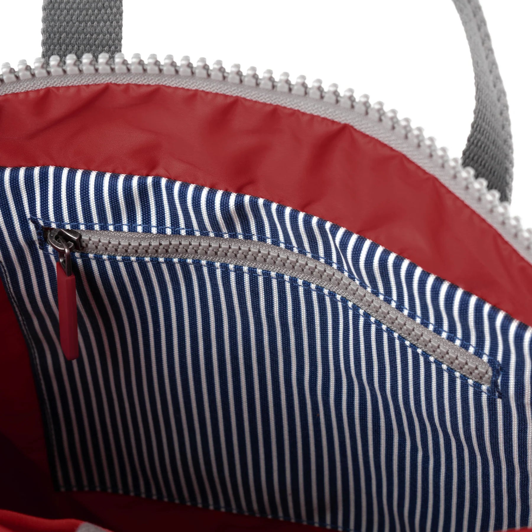 Close-up of a bag with red interior and blue striped pocket.