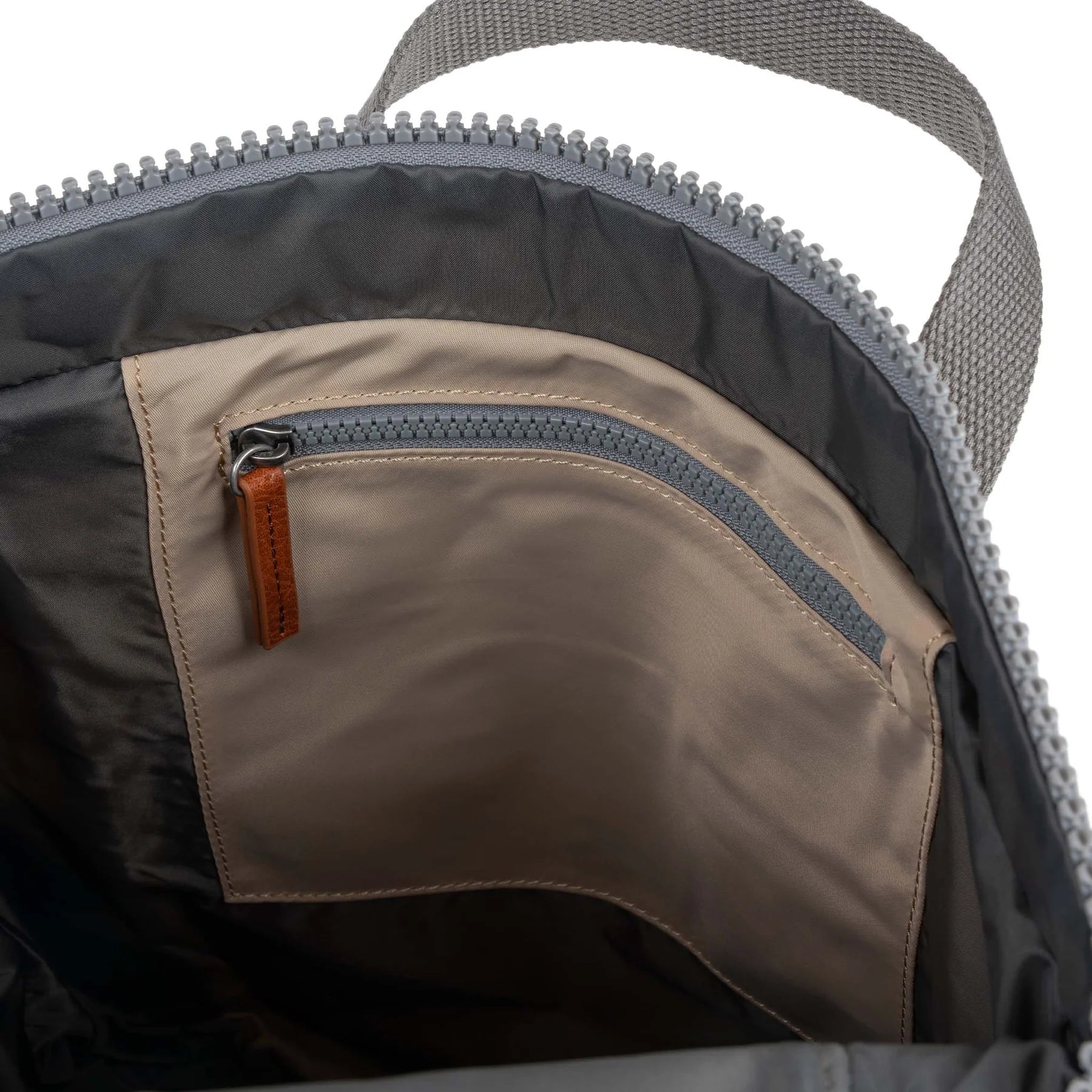 Close-up of a backpack with a zipper and brown interior pocket.