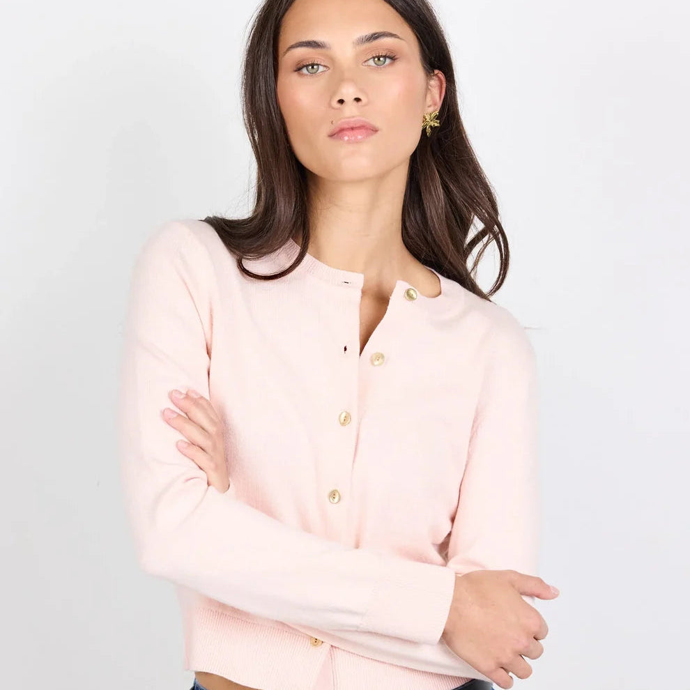 Woman wearing a light pink blouse and blue jeans against a white background