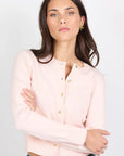 Woman wearing a light pink blouse and blue jeans against a white background