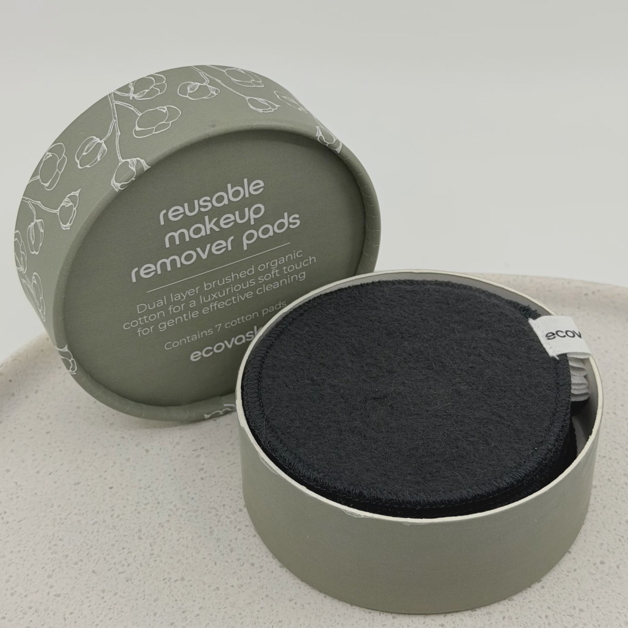 Reusable makeup remover pads in a green container on a light gray background