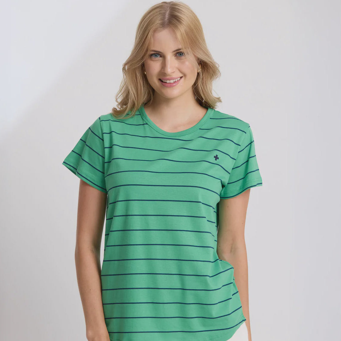Woman wearing a green striped shirt with a small logo on a white background
