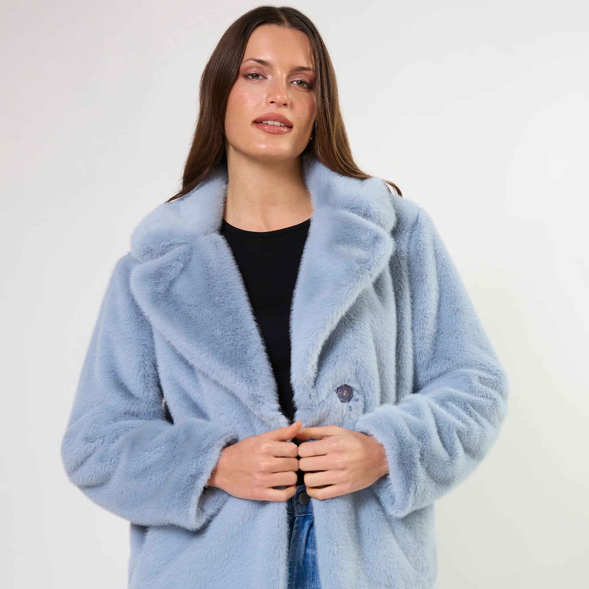 Woman wearing a light blue faux fur coat on a white background