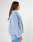 Woman wearing a light blue fluffy jacket on a white background