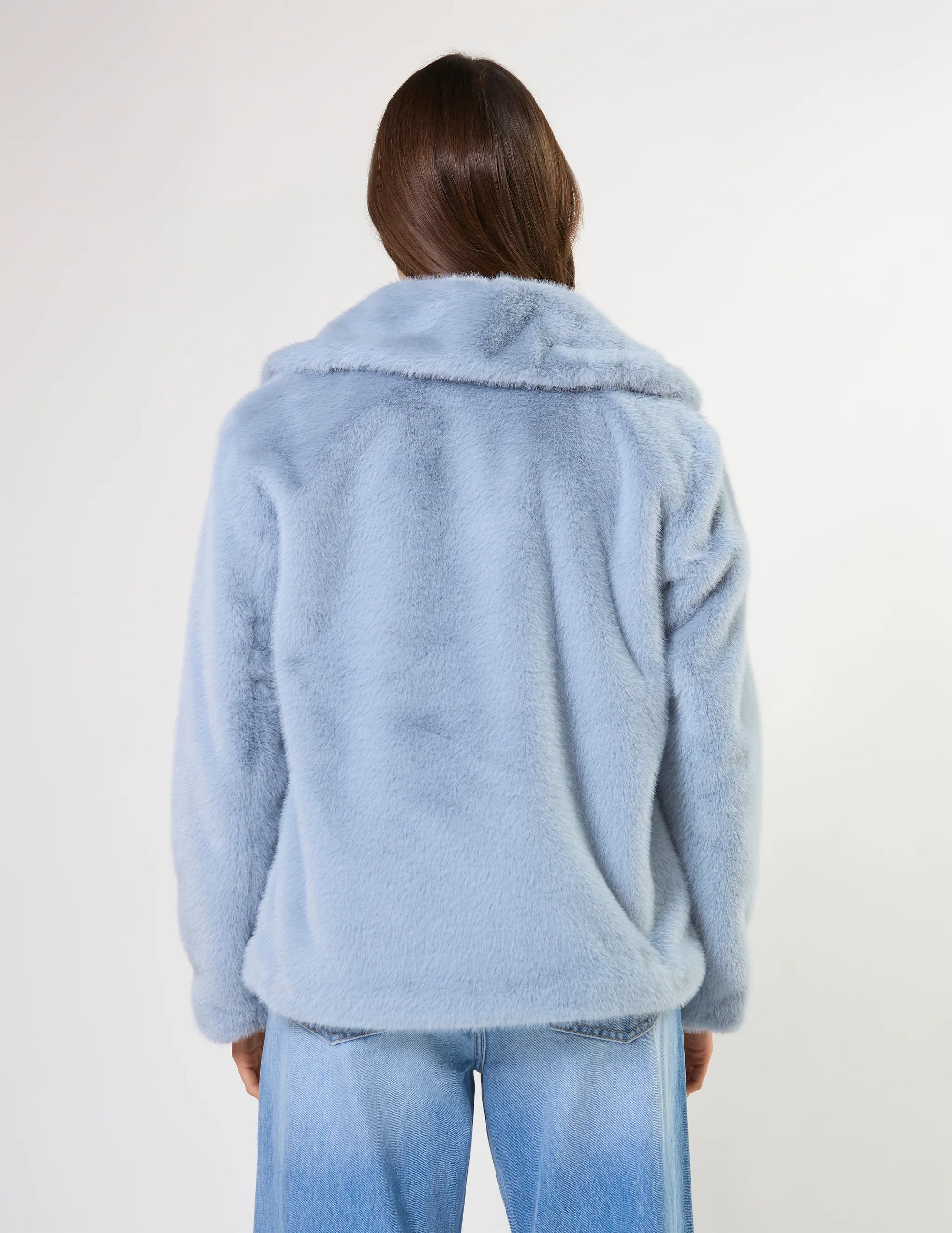 Person wearing a light blue fluffy jacket on a white background