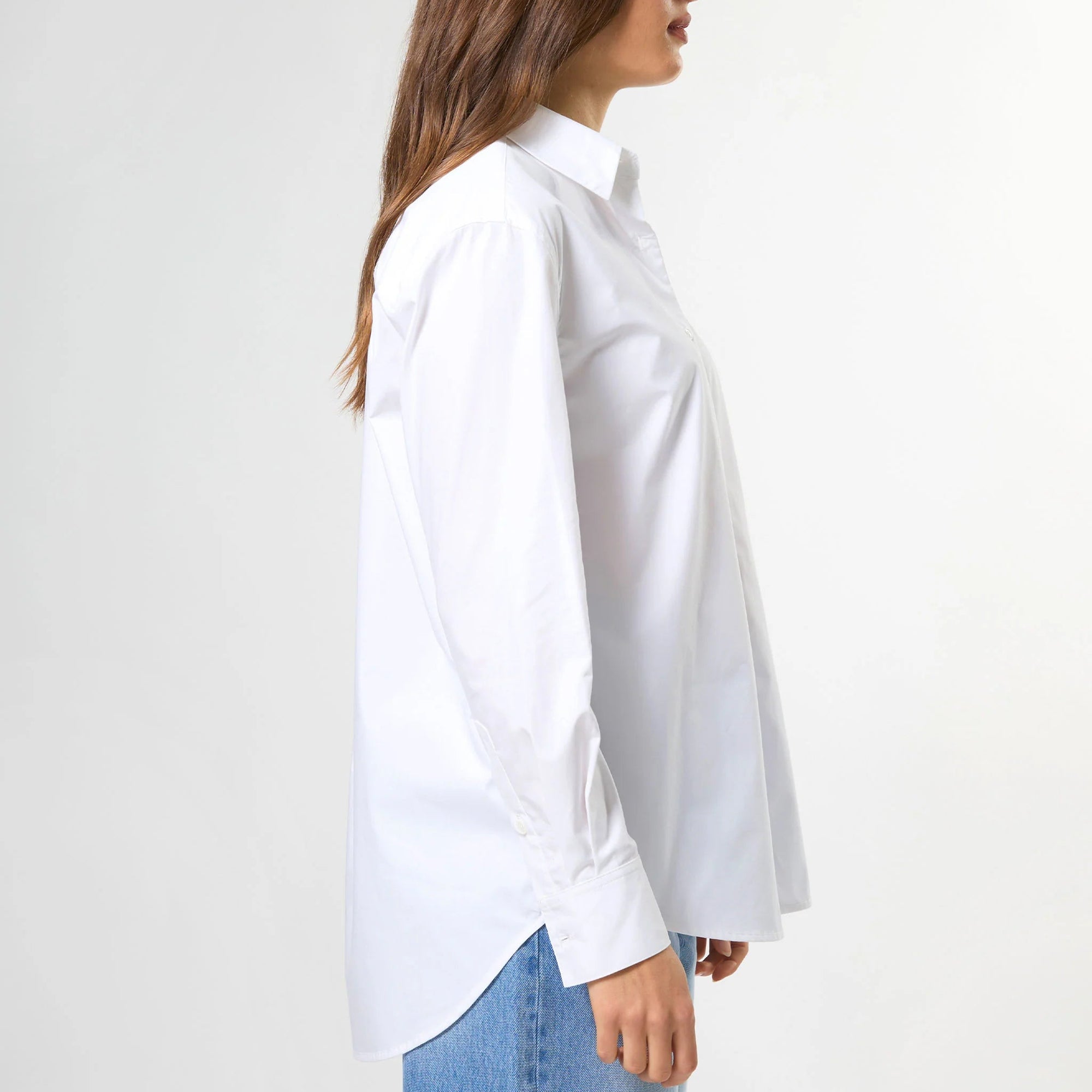 Woman wearing a white shirt and blue jeans against a white background