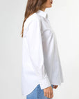 Woman wearing a white shirt and blue jeans against a white background
