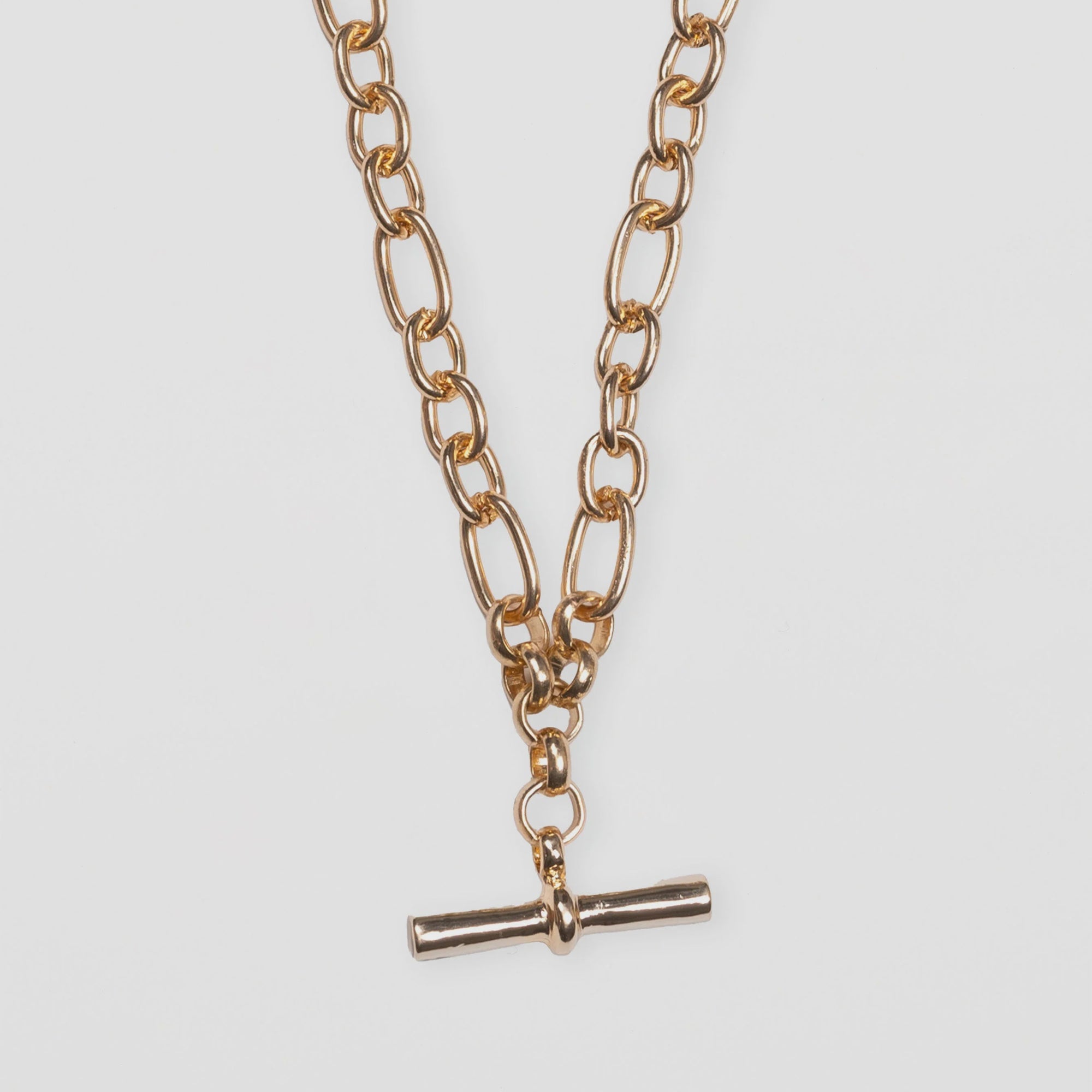 Gold chain necklace with a small pendant on a light gray background