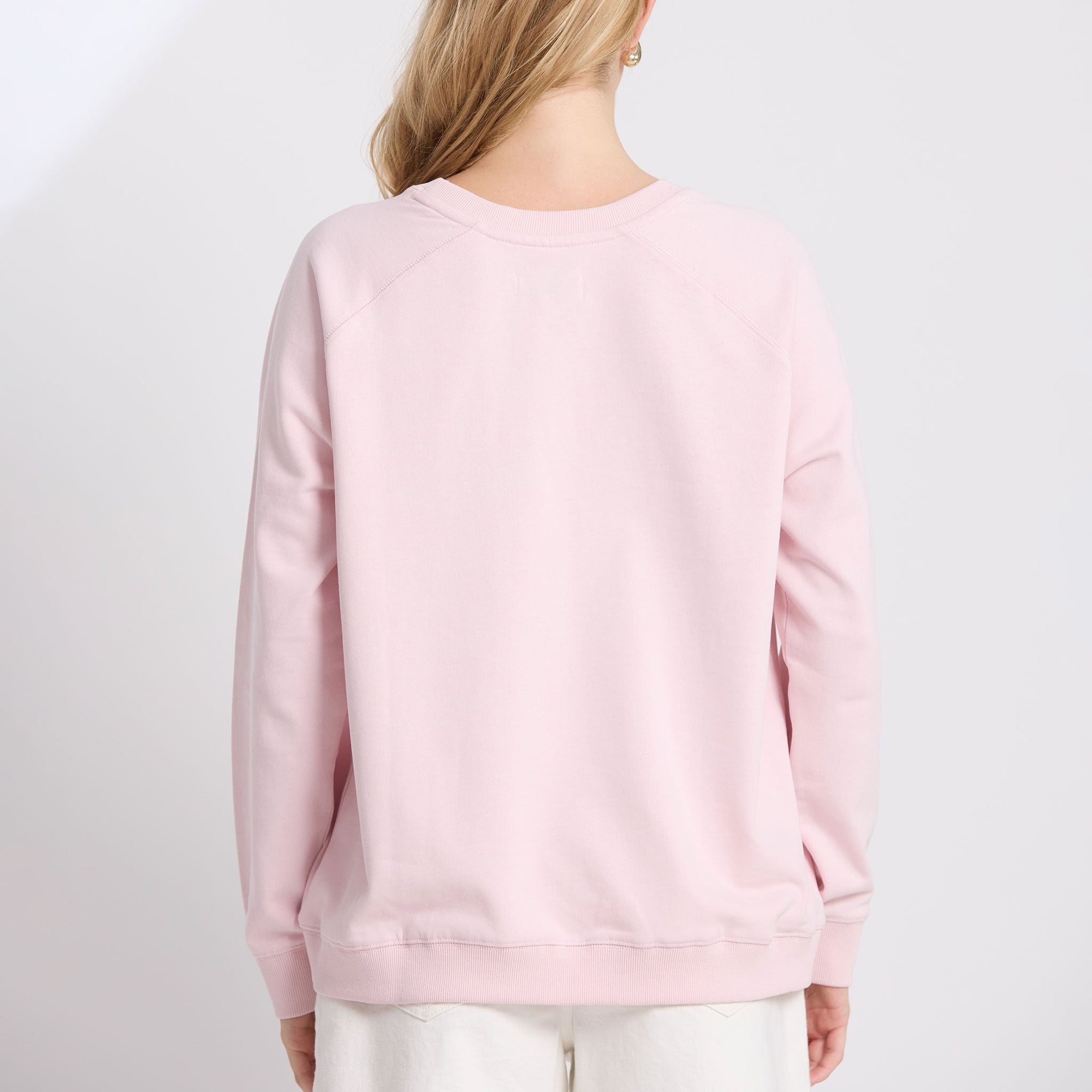 Person wearing a light pink sweatshirt on a white background