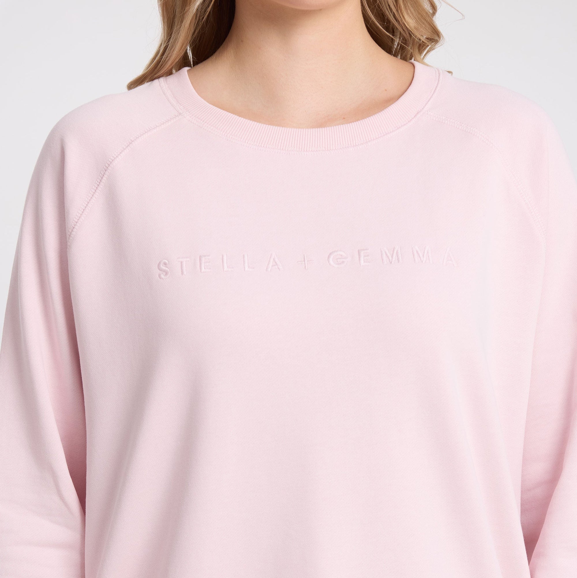 Pink sweatshirt with a brand logo on a light gray background