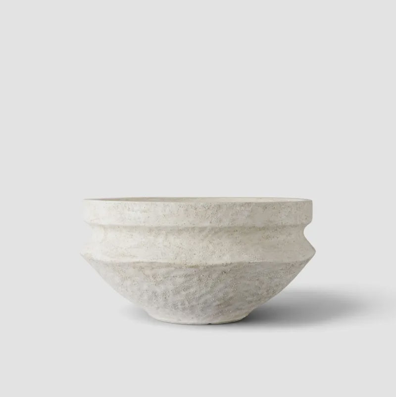 A textured, handcrafted ceramic bowl in a light warm gray or off-white glaze, photographed against a clean white background with a soft shadow.