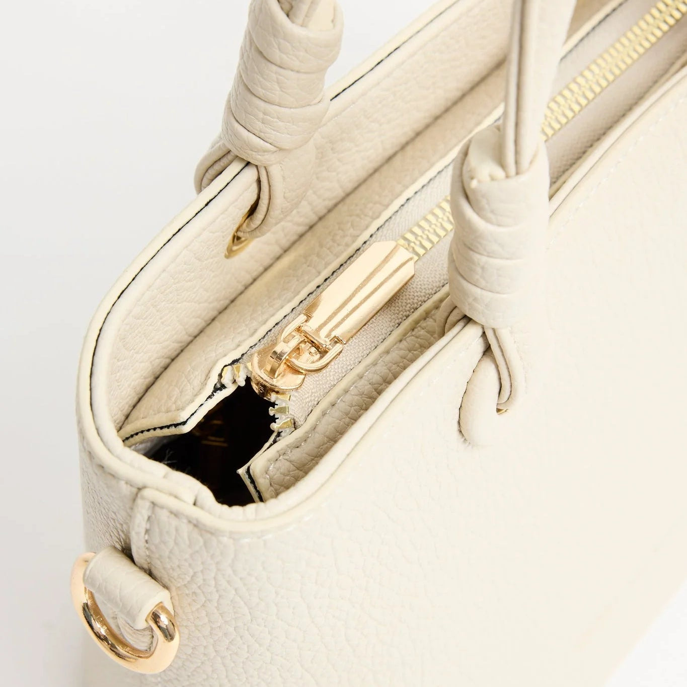 Close-up of a beige handbag with gold accents on a white background