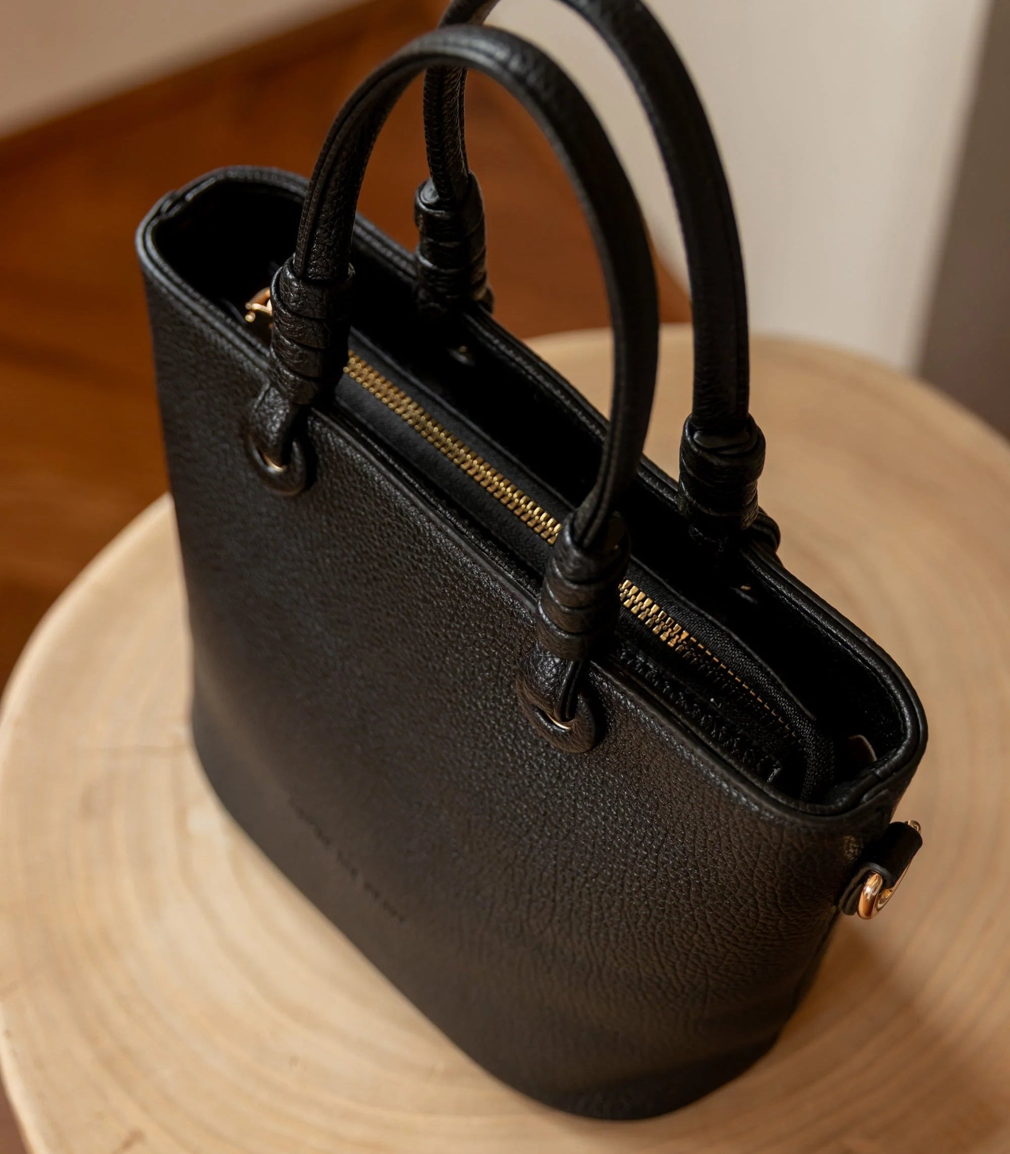 Black handbag on a wooden surface with a neutral background